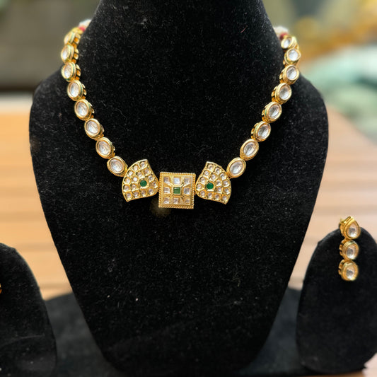 A double-sided Kundan necklace with intricate handcrafted designs and stunning Kundan stones displayed on a black stand.