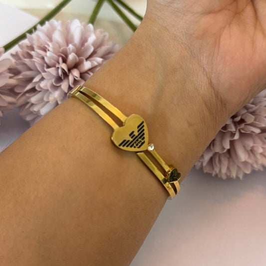 Gold bracelet on a wrist with pink flowers in the background