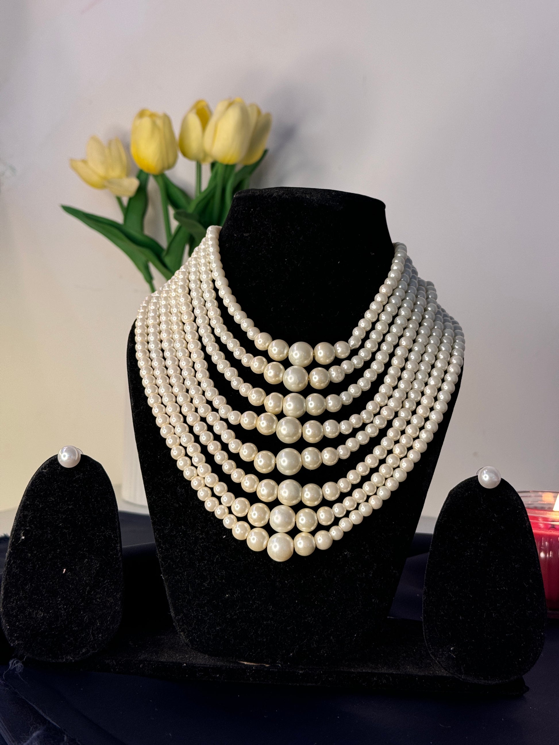 Pearl headband on a black stand with yellow tulips in the background