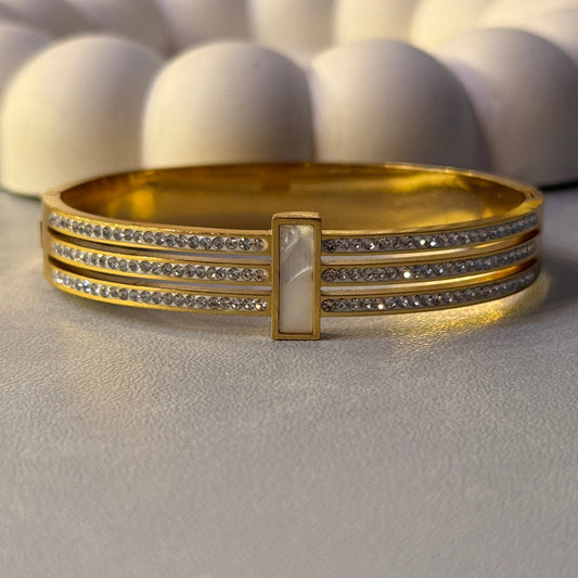 Gold bracelet with gemstone accents on a textured surface