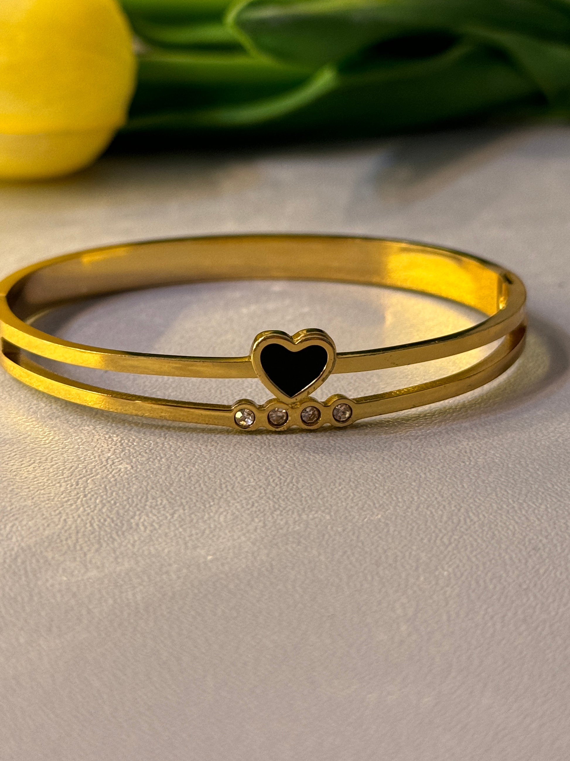 Gold bracelet with a heart-shaped charm on a light gray background