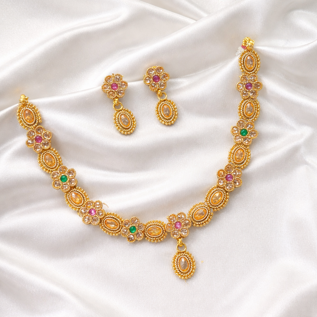 Gold necklace with colorful stones on a white fabric background