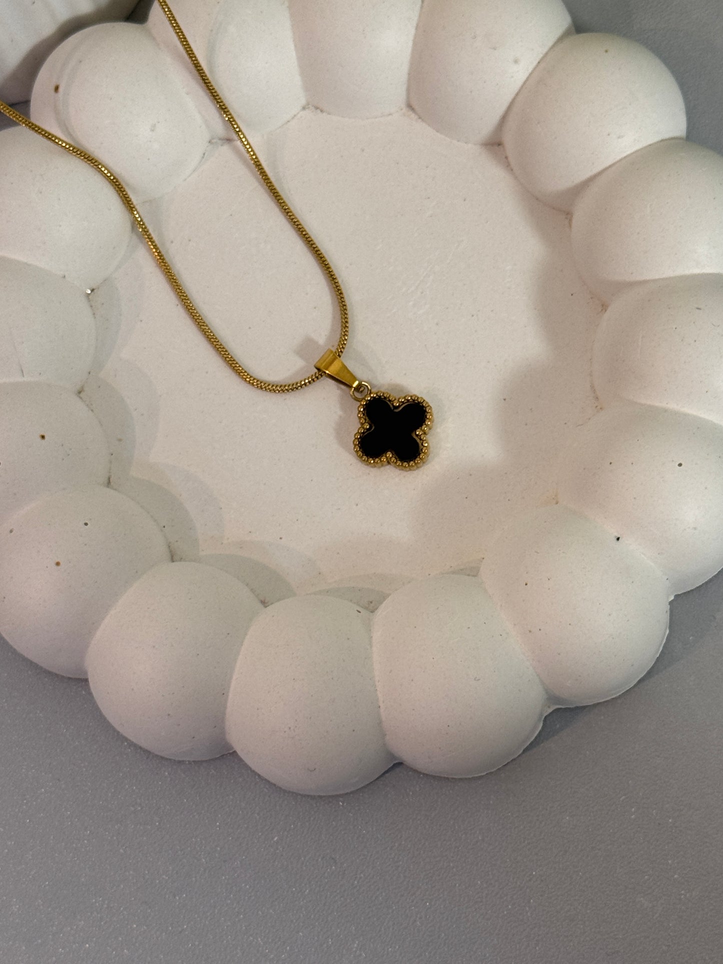 Necklace with a clover-shaped pendant on a white beaded stand.