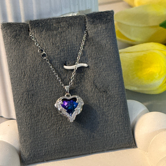 Necklace with a heart-shaped purple gemstone on a gray card with yellow tulips in the background