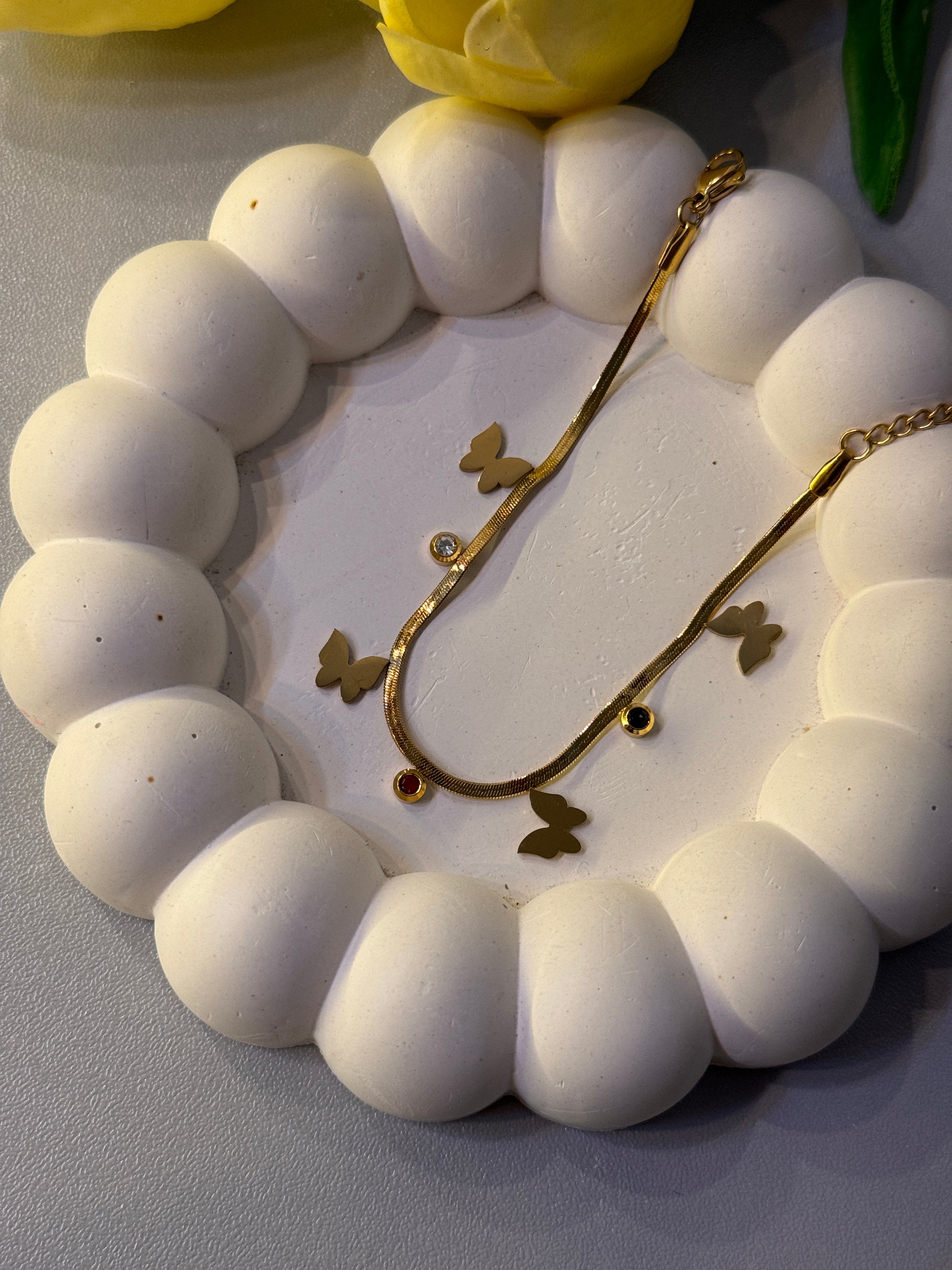 White beaded bracelet with gold butterfly charm on a white background