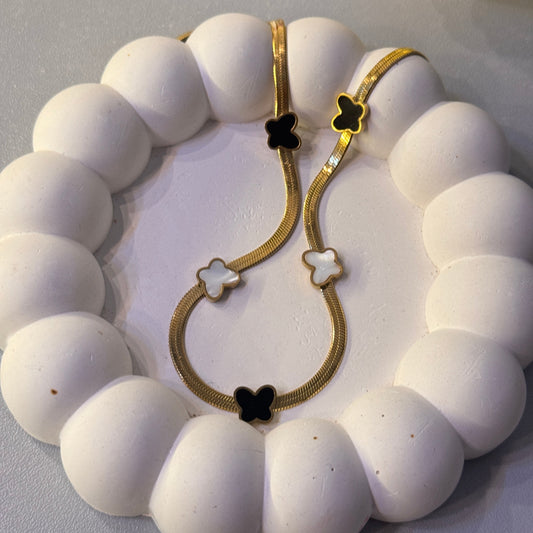 White beaded bracelet with gold clasp on a white surface