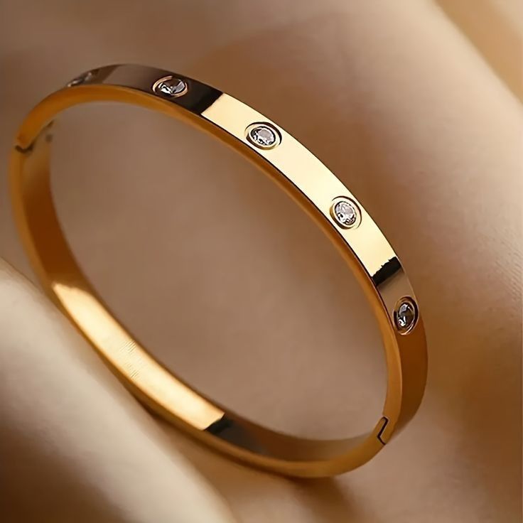 Gold bracelet with diamond accents on a beige background