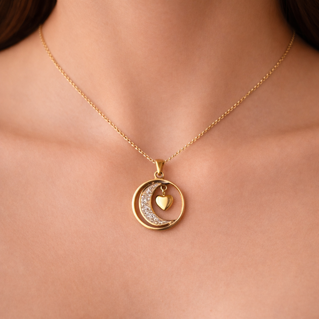 Gold necklace with a heart and crescent moon pendant on a person's neck.