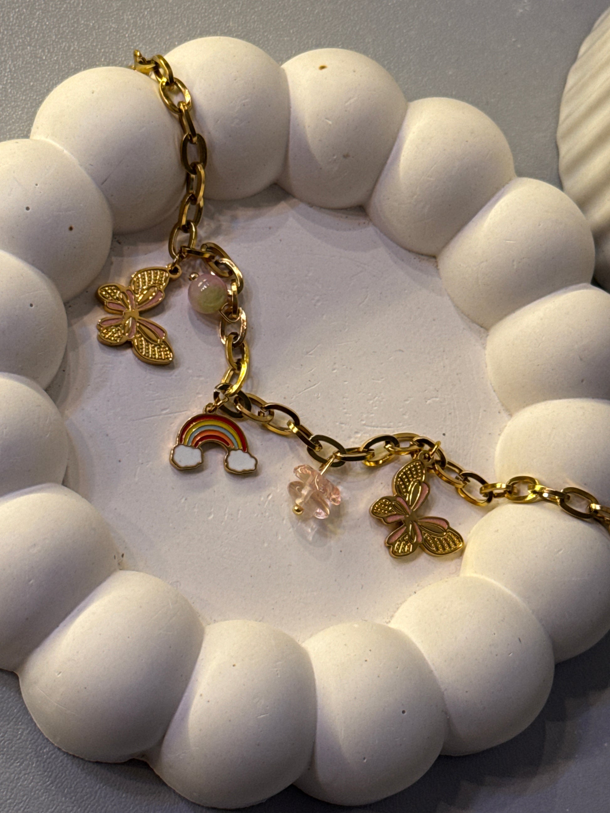 Bracelet with gold charms on a white beaded surface