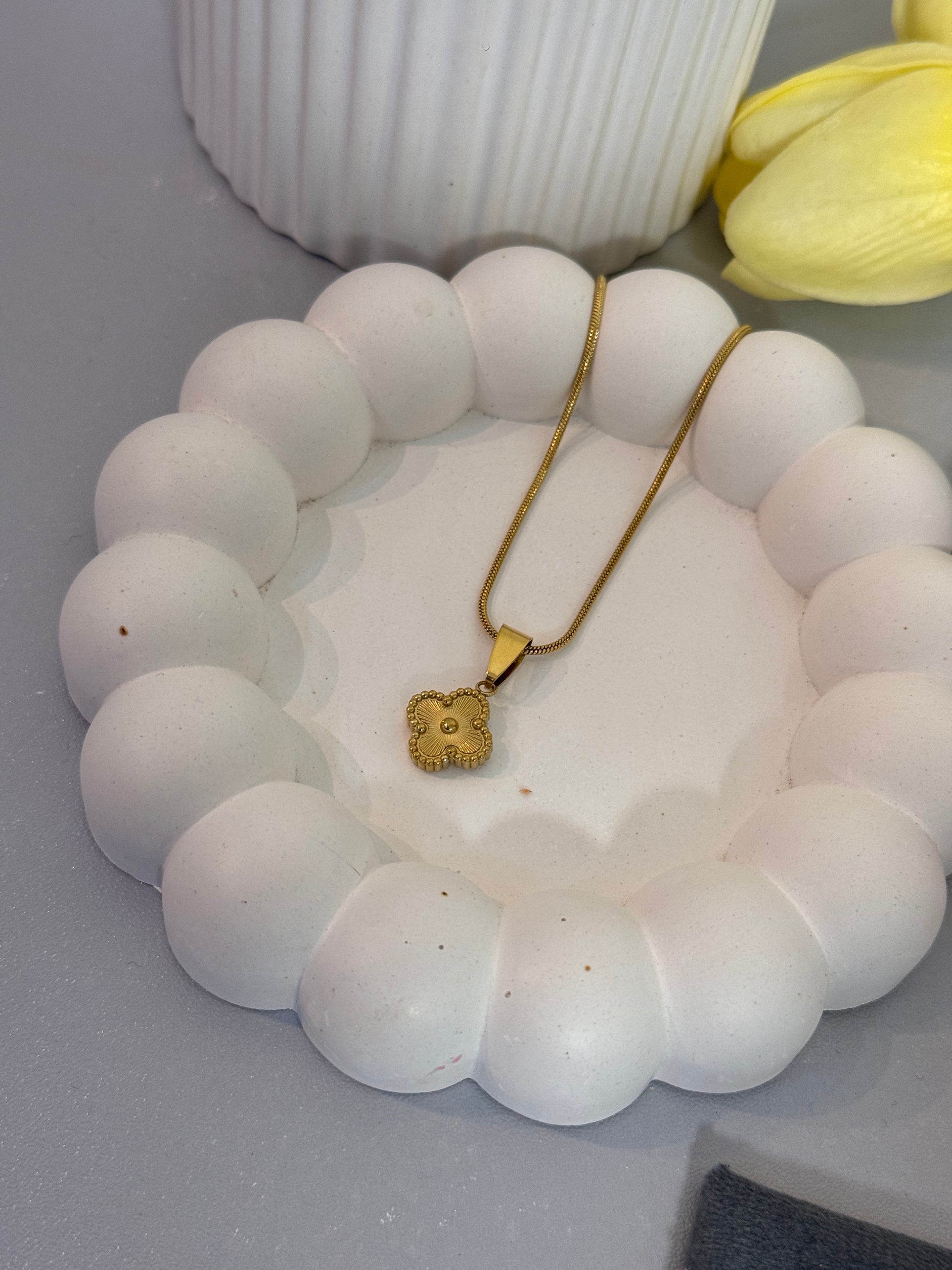 White beaded bracelet with a gold clasp on a white surface