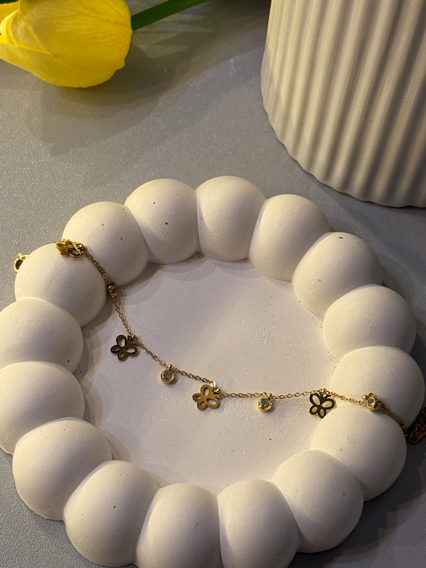 Gold necklace with floral pendants on a white textured surface