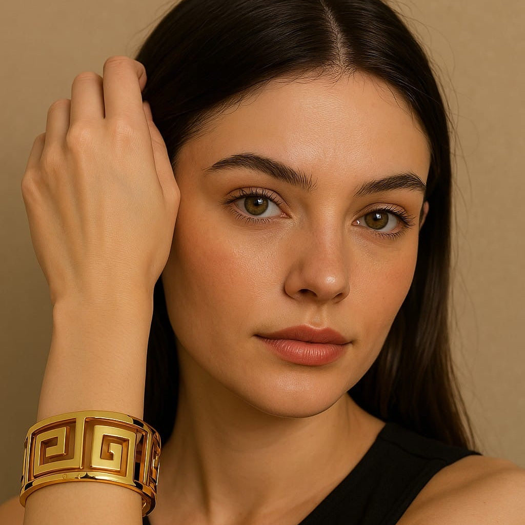 A person showcasing a gold-colored square-shaped bracelet on their wrist.