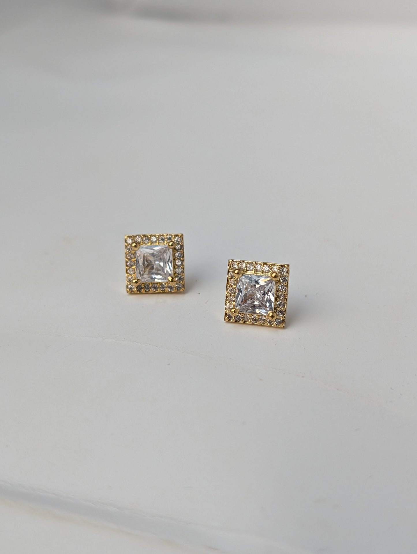 Pair of square-cut gemstone earrings with gold accents on a light gray background