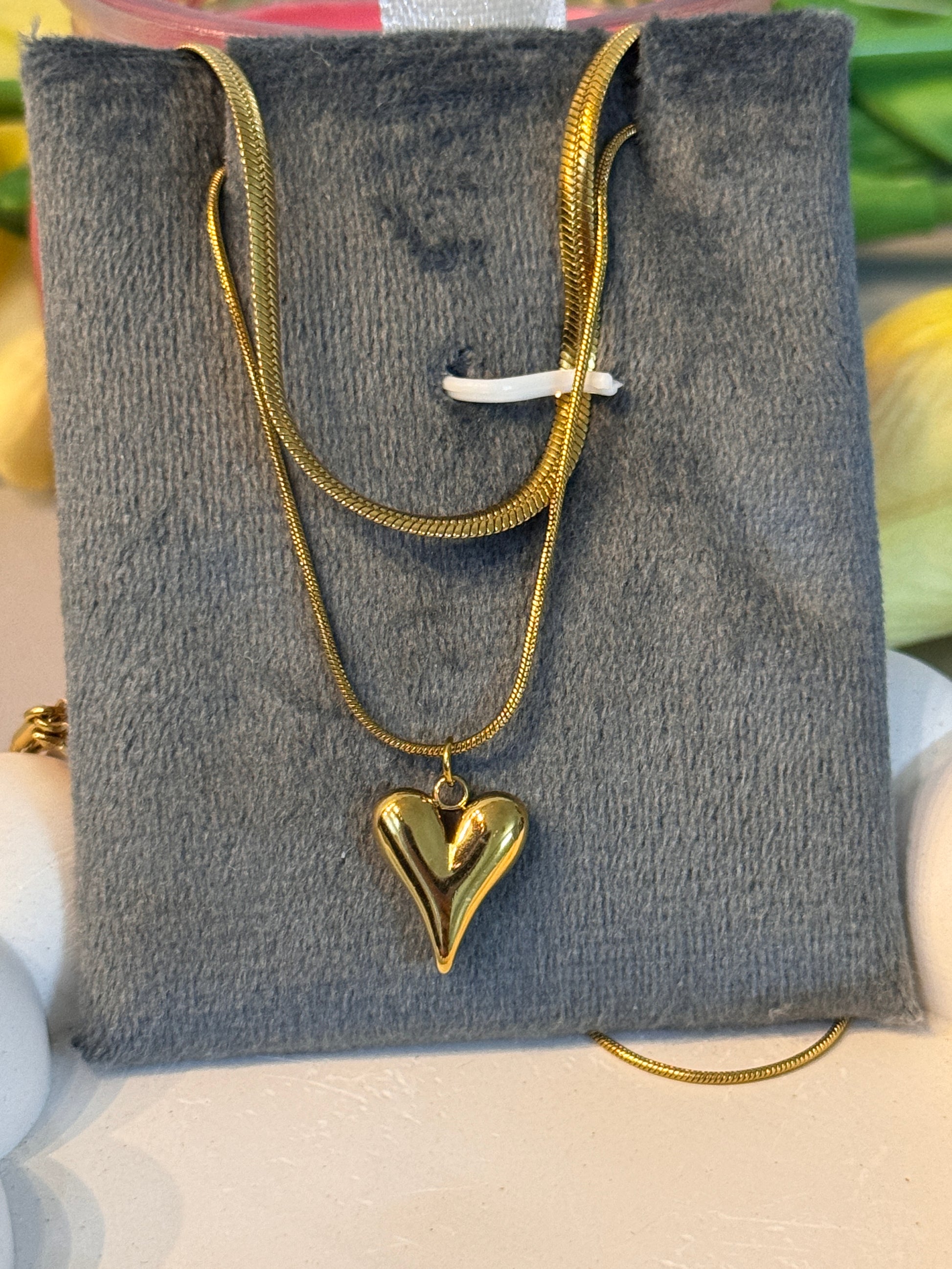 Gold necklace with a heart pendant on a gray surface