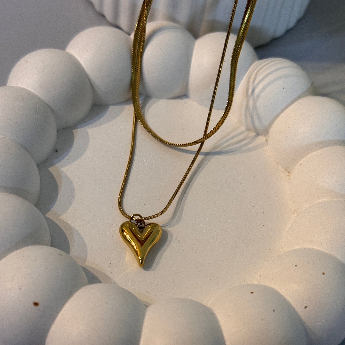 Close-up of a white ceramic wall art piece with gold accents