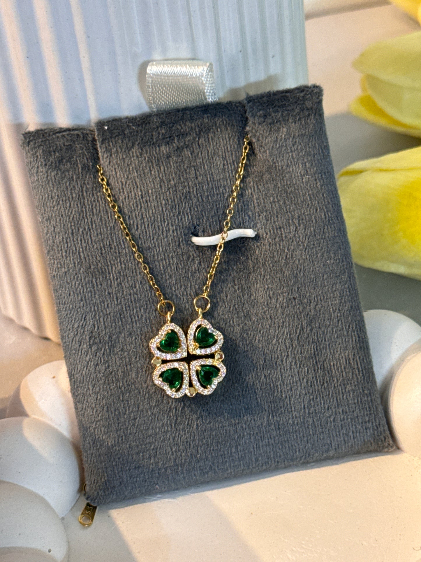 Gold necklace with green gemstone pendant on a gray jewelry box