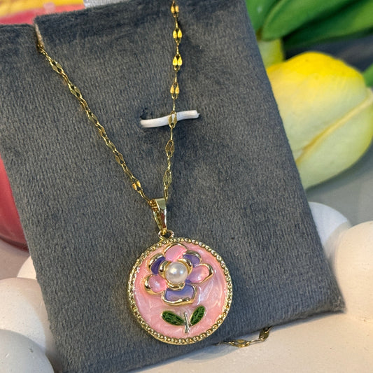 Necklace with a floral pendant on a gray card, with flowers in the background