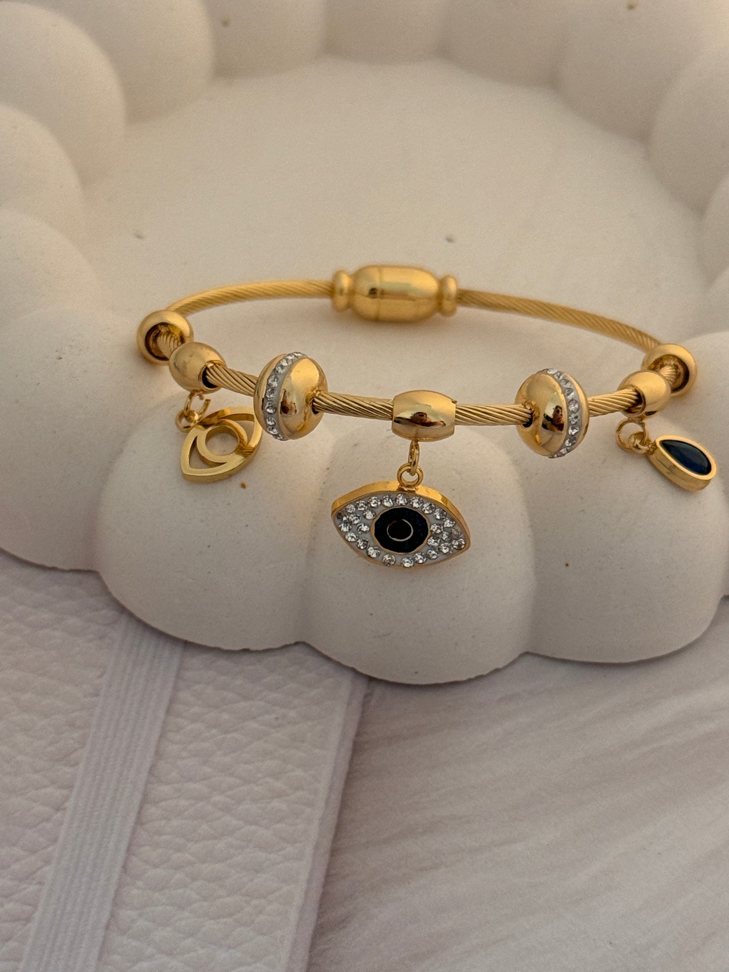 Gold bracelet with charms on a textured white surface