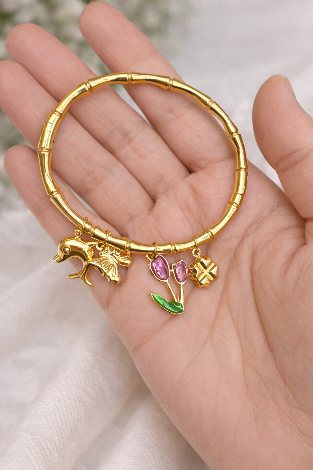 Gold bracelet with charms on a hand against a soft background