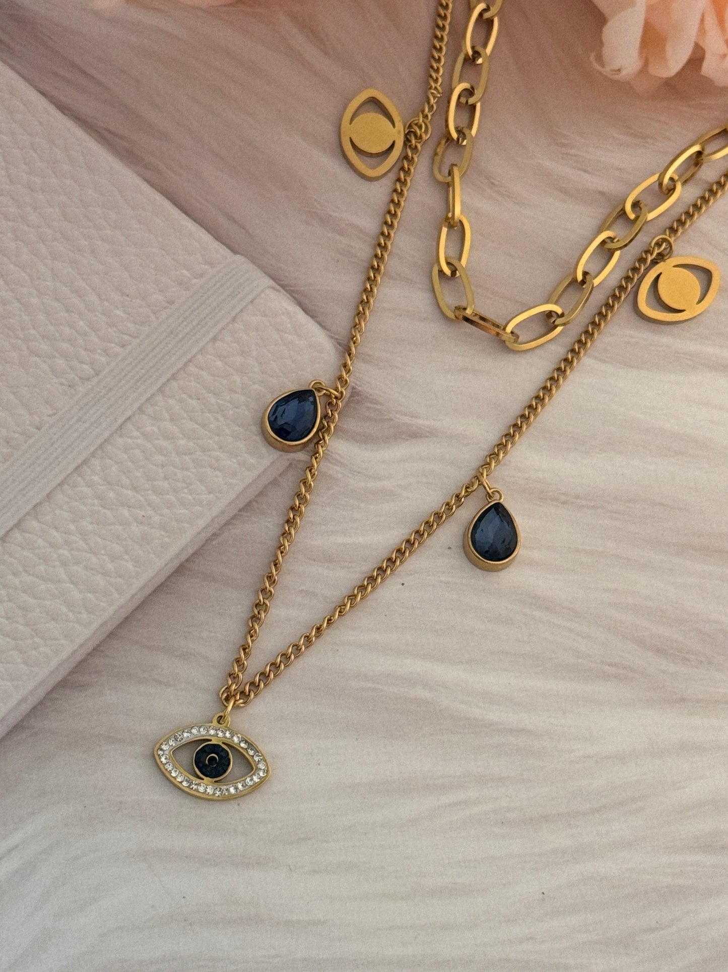 Gold chain necklaces with blue stone pendants on a light wooden surface