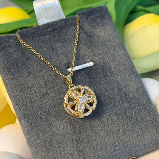 Gold necklace with a decorative pendant on a gray cushion