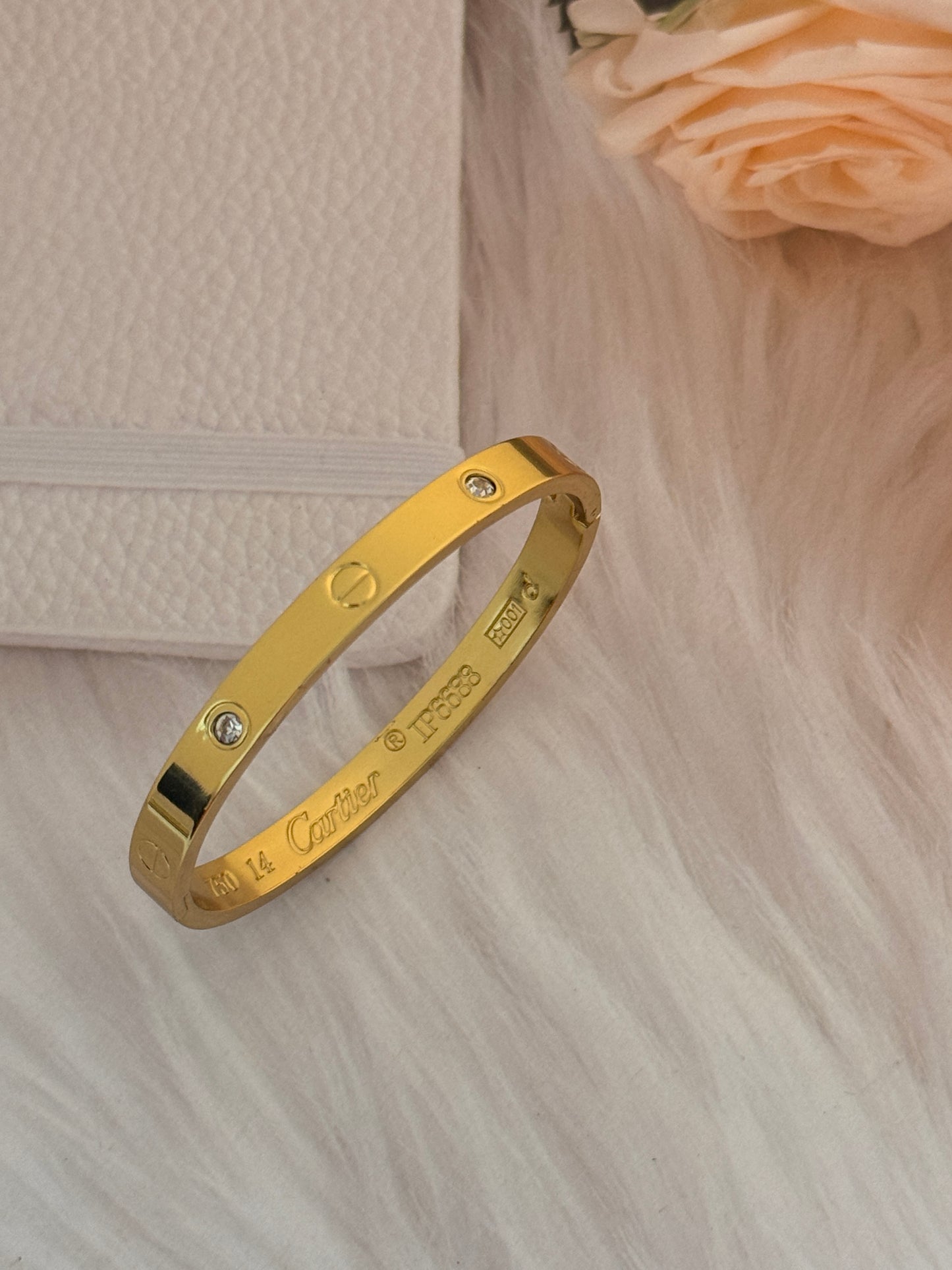 Gold bracelet with engraved text on a soft fabric background