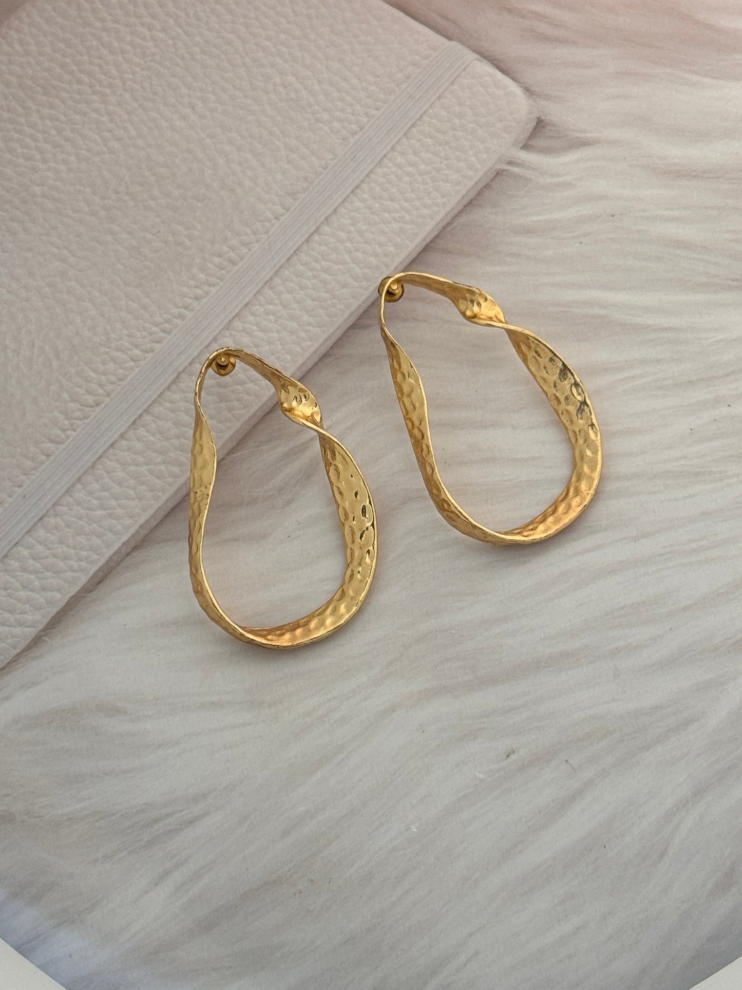 Gold hoop earrings on a textured surface