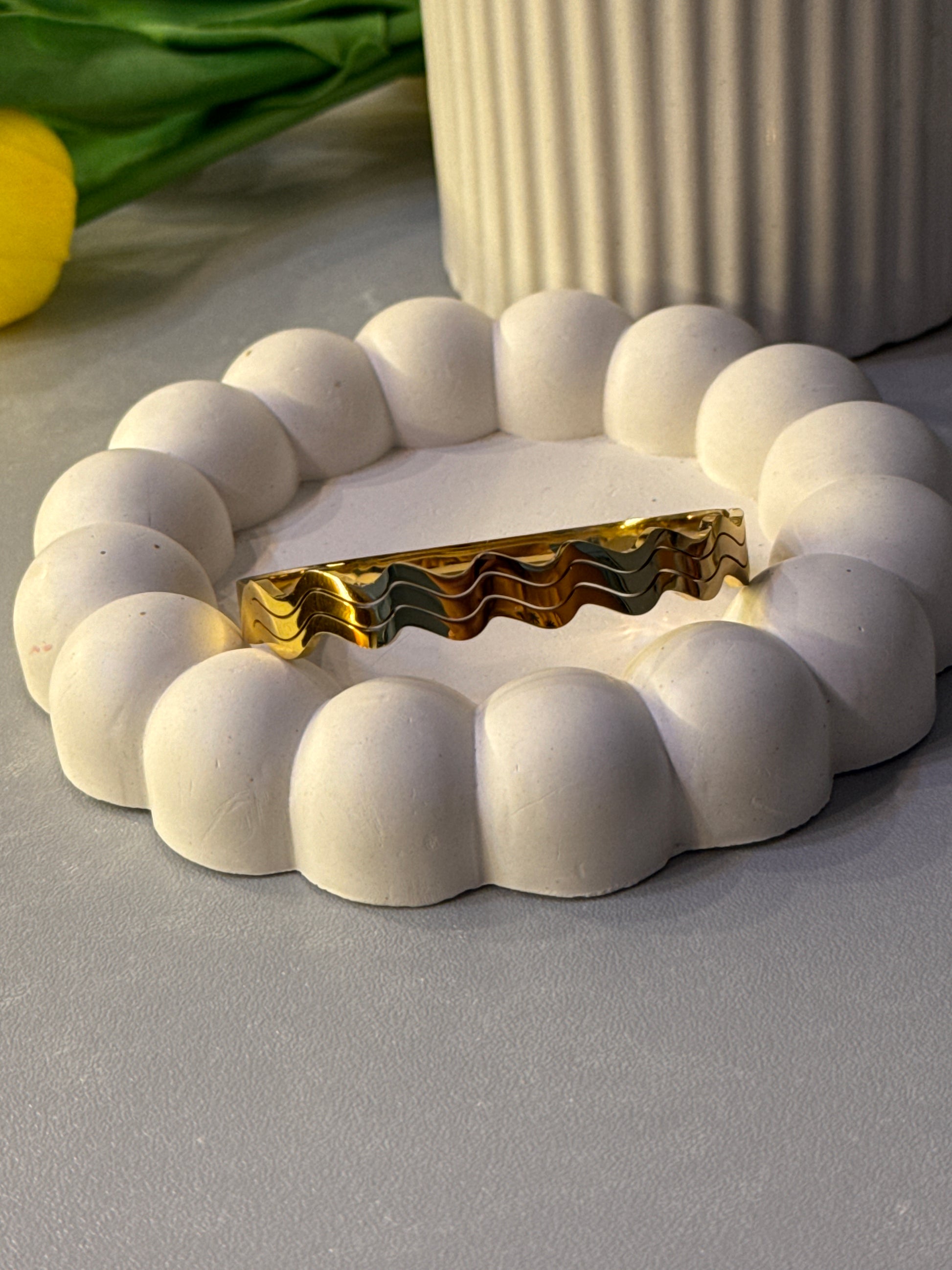 Decorative wall piece with white spherical beads and gold center on a gray wall.