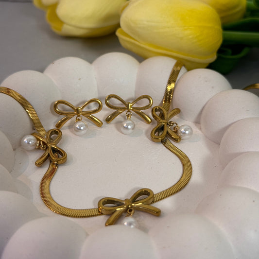 Gold bracelet with bow and pearl details on a white flower background