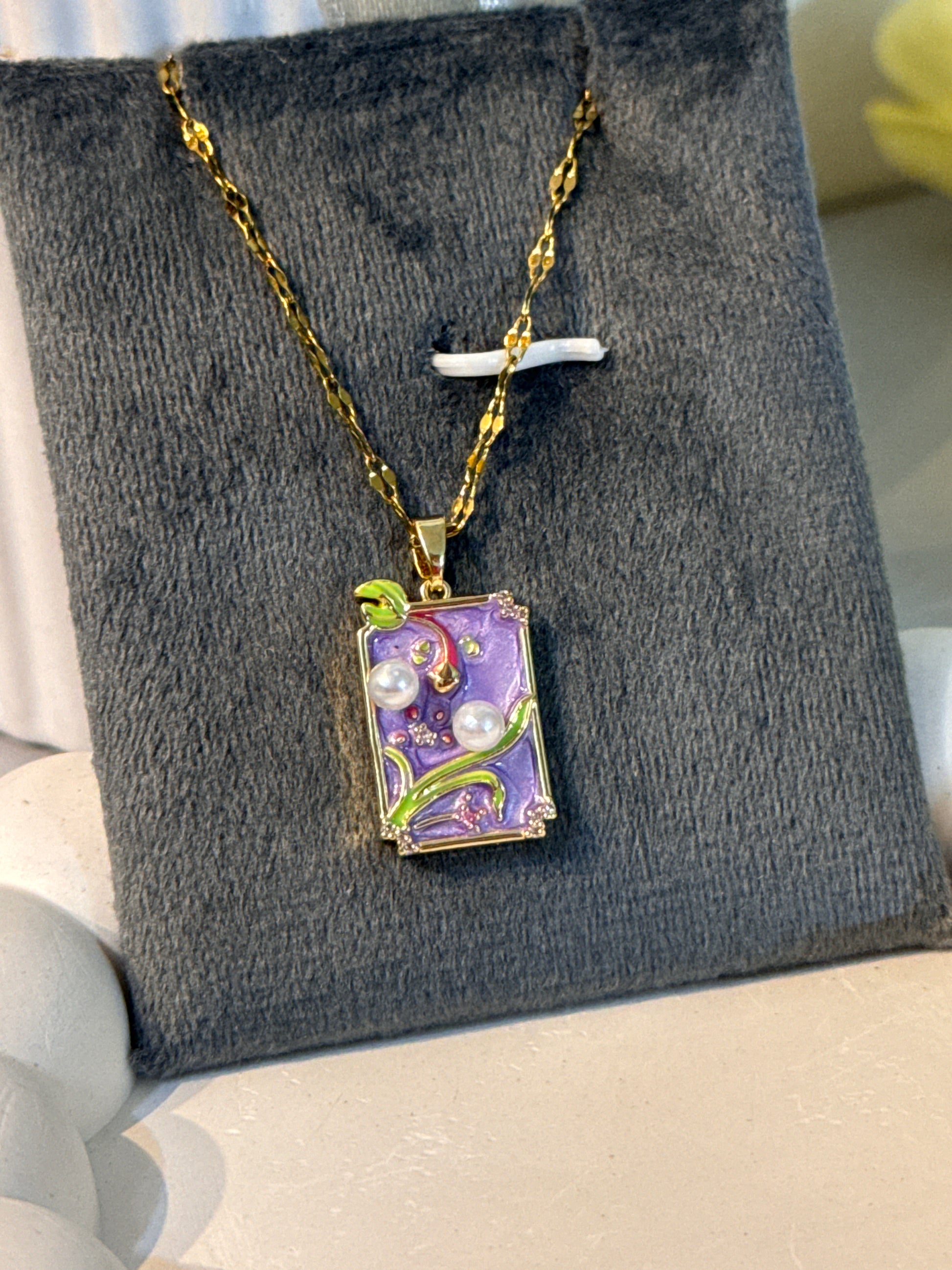 Decorative pendant on a gold chain on a gray display box