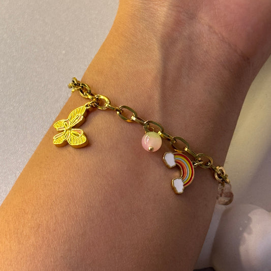 Gold bracelet with butterfly and rainbow charm on wrist