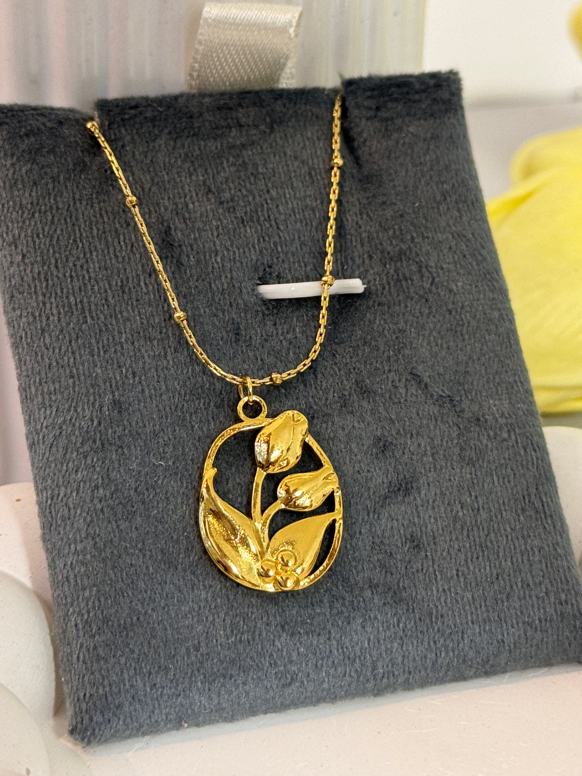 Gold necklace with a floral pendant on a gray surface