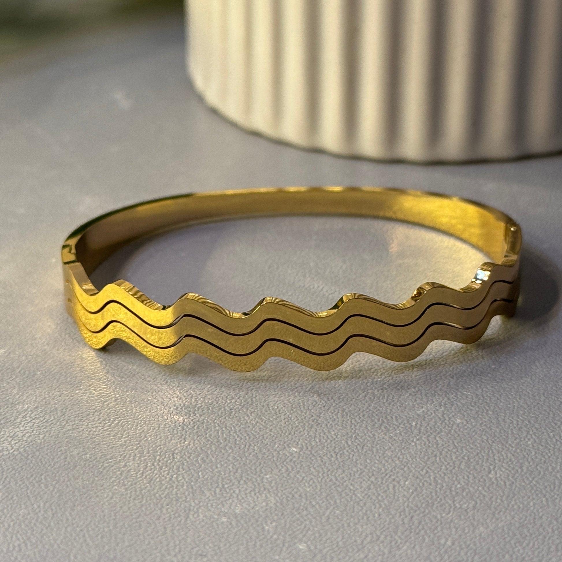 Gold ring with wavy pattern on a metallic surface