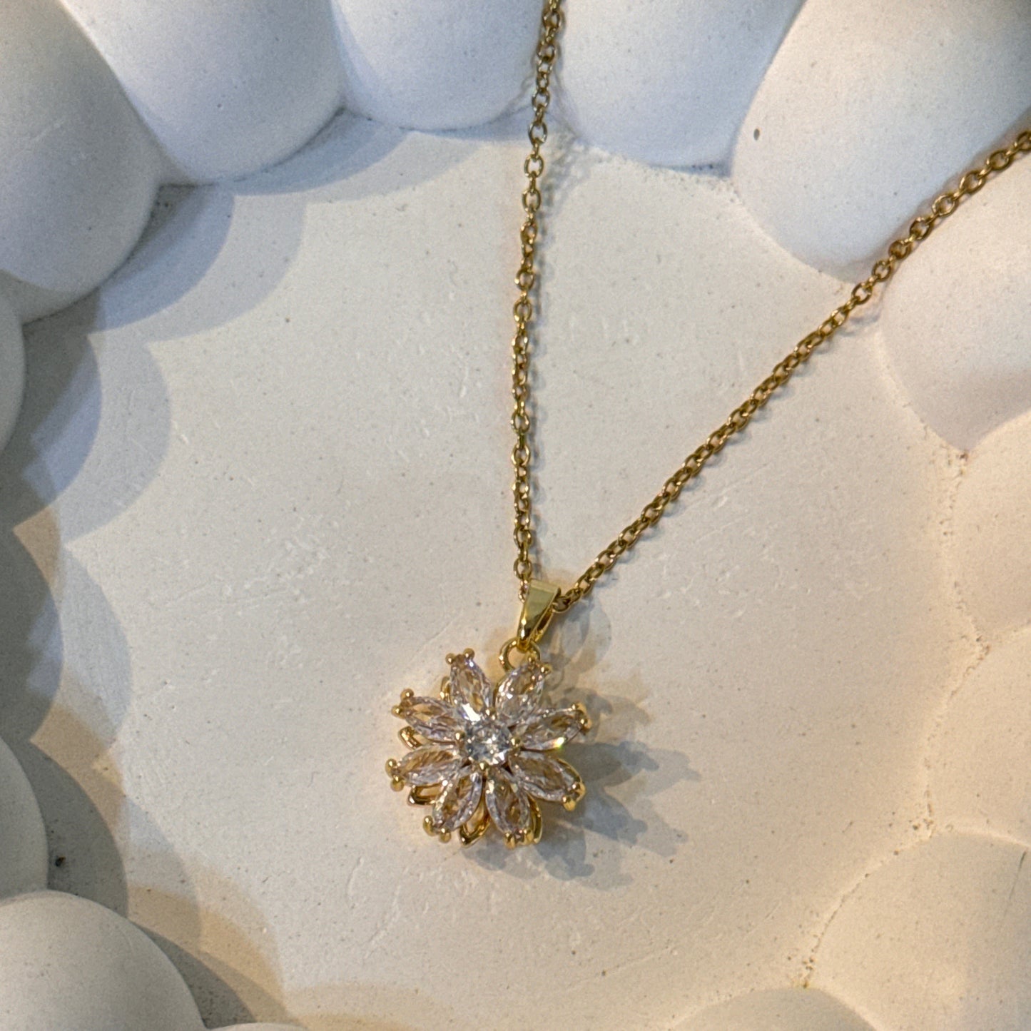 Gold necklace with a diamond pendant on a textured white surface
