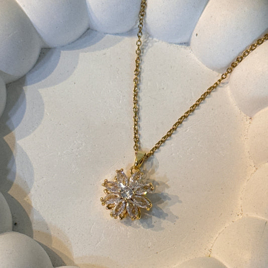 Gold necklace with a diamond pendant on a textured white surface