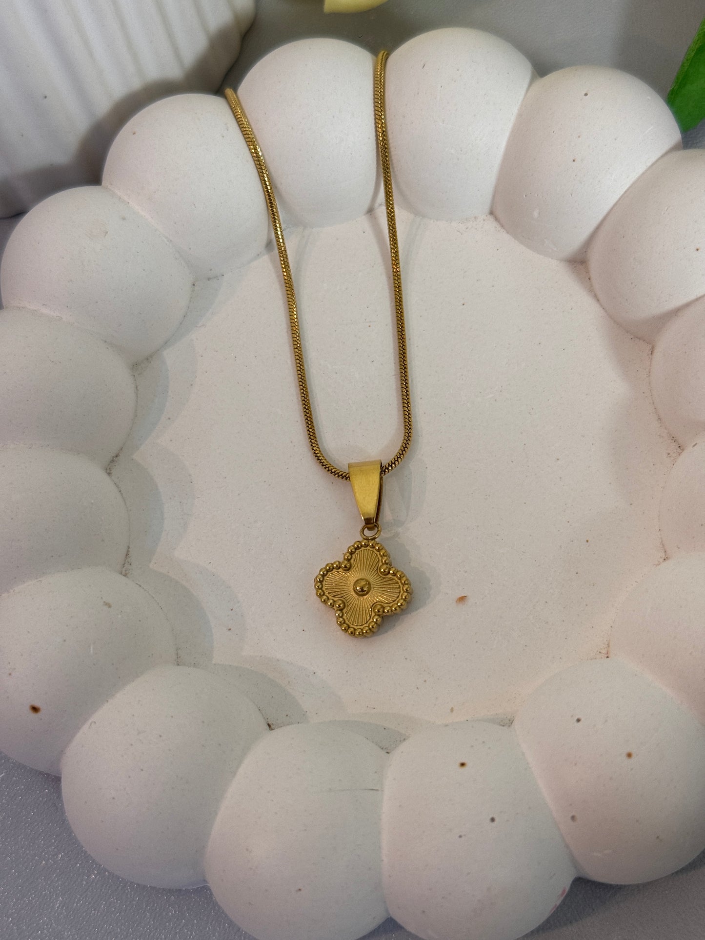 Gold necklace with a decorative pendant on a white stone surface