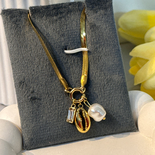 Gold bracelet with charms on a gray velvet pillow