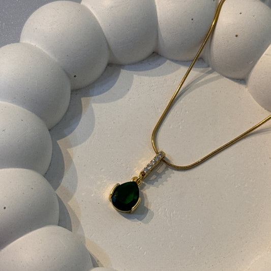 Necklace with a green pendant on a textured white surface