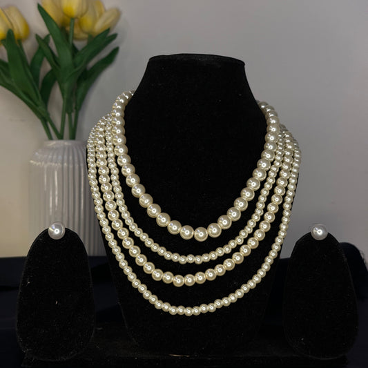 Set of pearl necklaces on a black stand with yellow tulips in the background