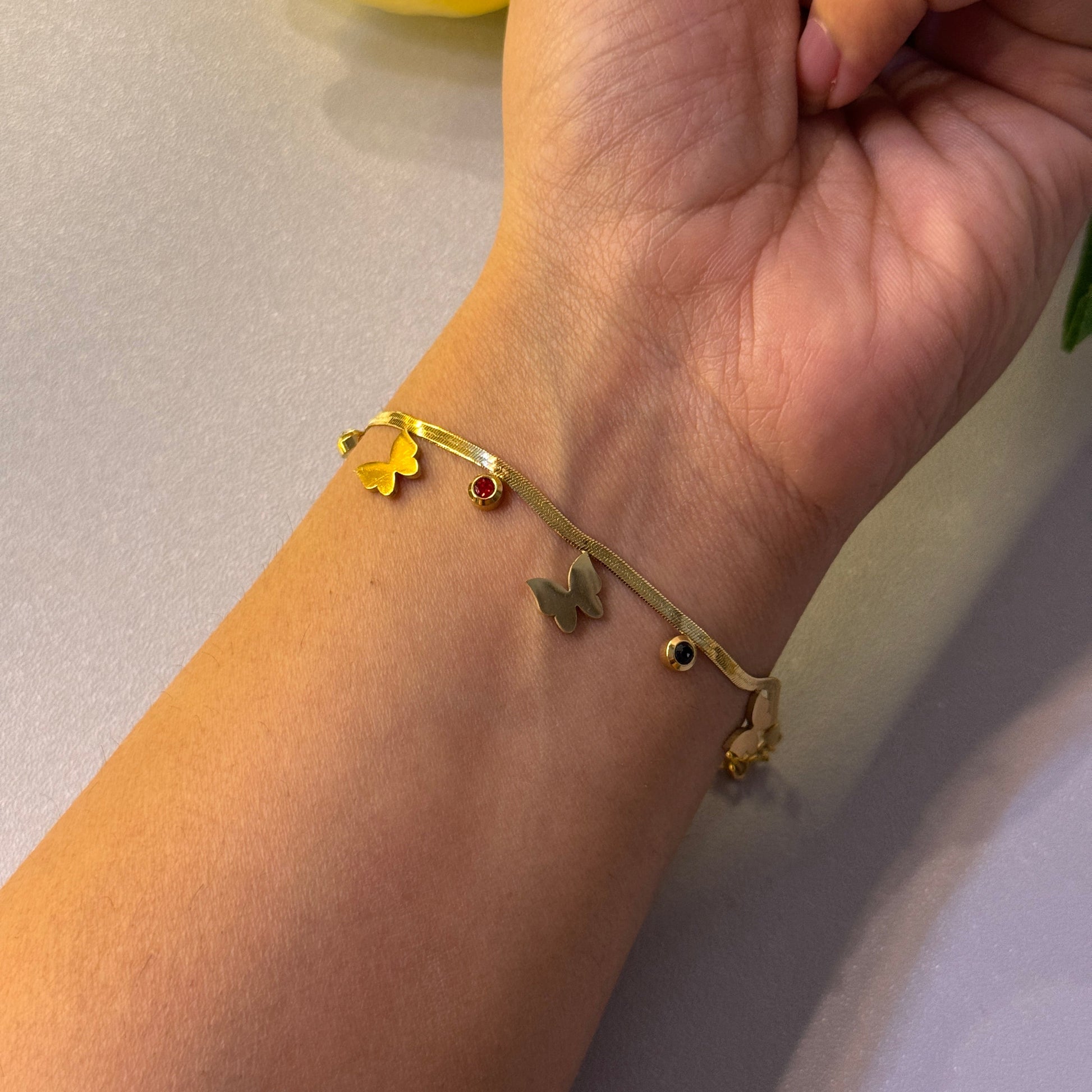 Gold bracelet with star-shaped charms on a wrist against a neutral background