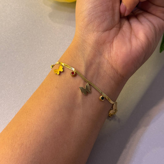 Gold bracelet with star-shaped charms on a wrist against a neutral background