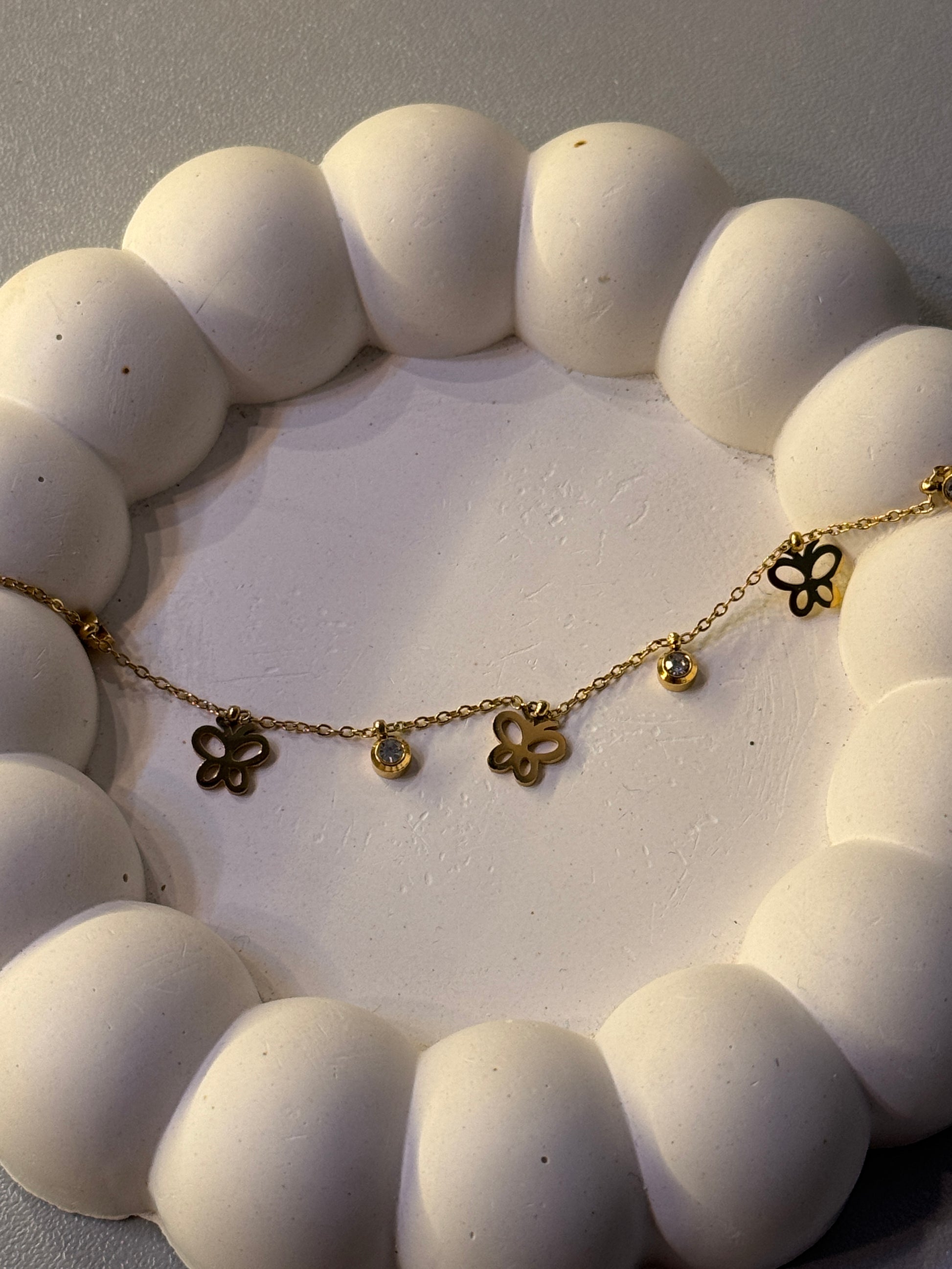 Gold necklace with floral pendants on a textured white surface