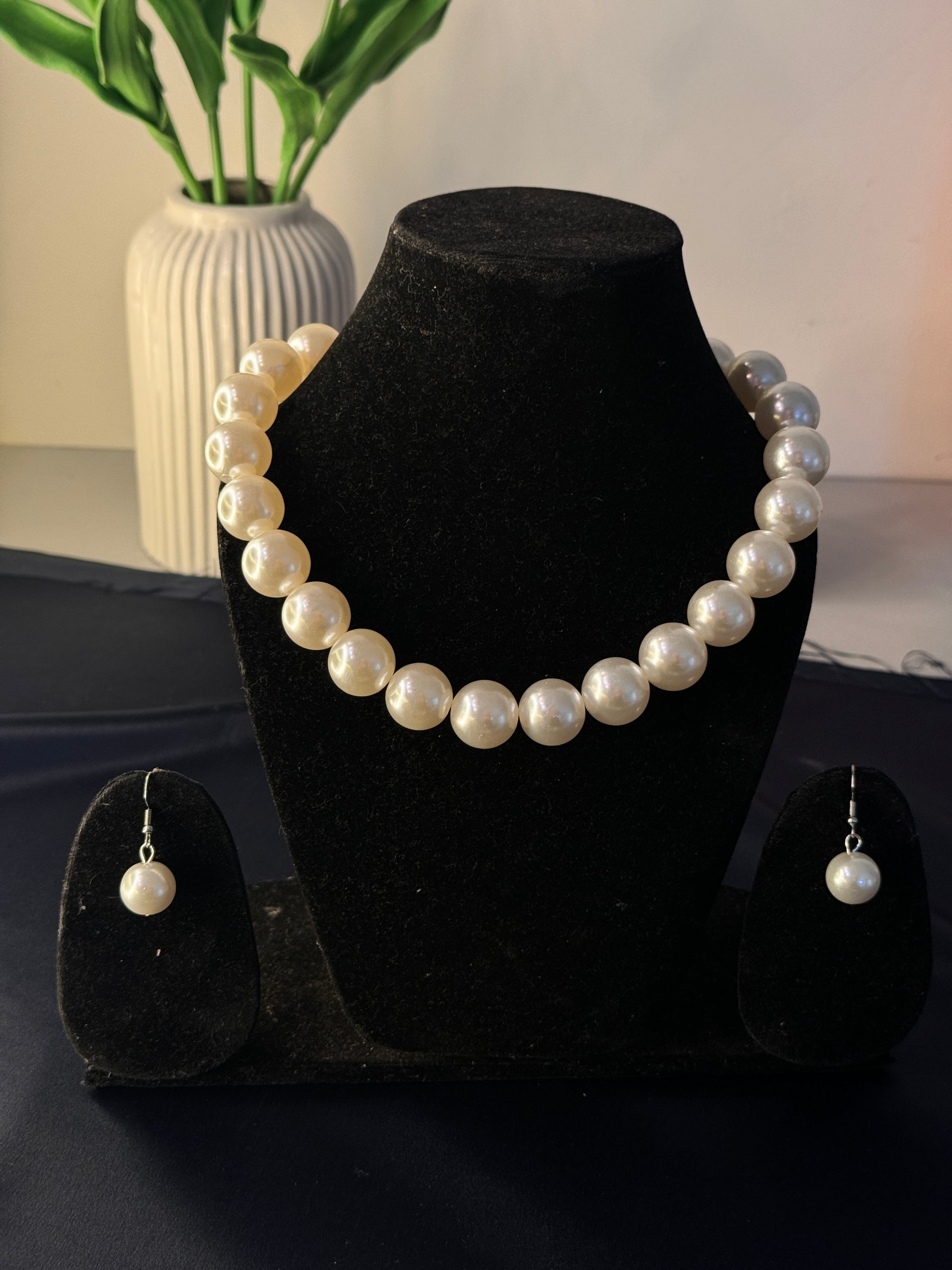 Pearl bracelet and earrings on a black stand with a blurred background
