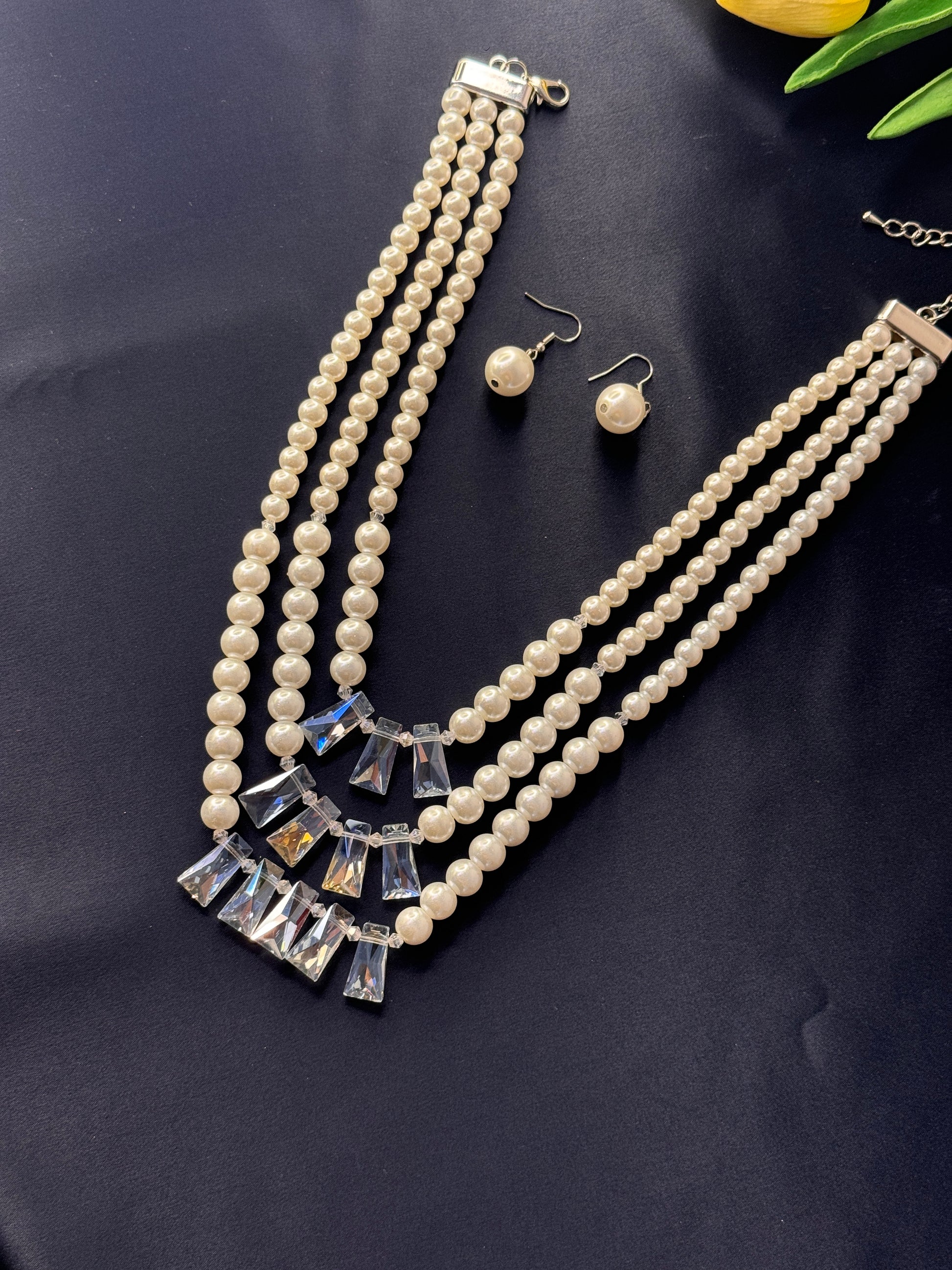 Pearl necklace with crystal accents and matching earrings on a dark surface