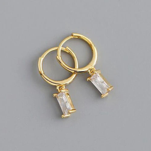 Gold hoop earrings with rectangular gemstones on a gray background