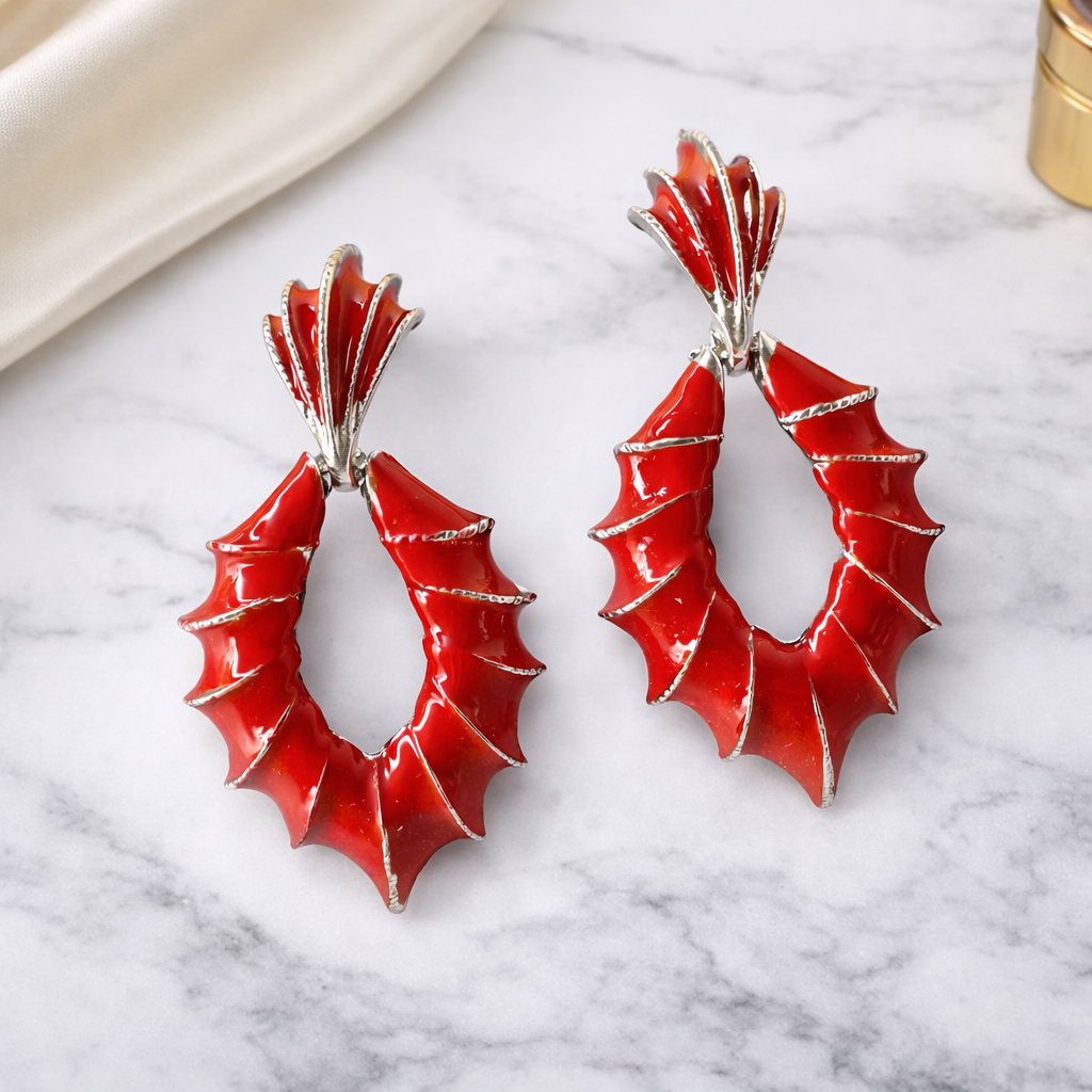 Red earrings with silver accents on a marble surface