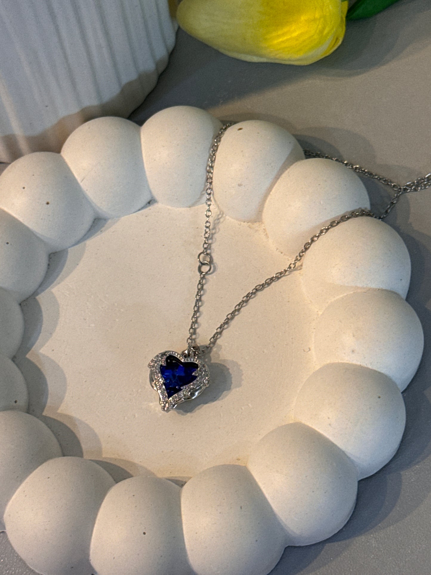 Necklace with a heart-shaped blue pendant on a white stone surface
