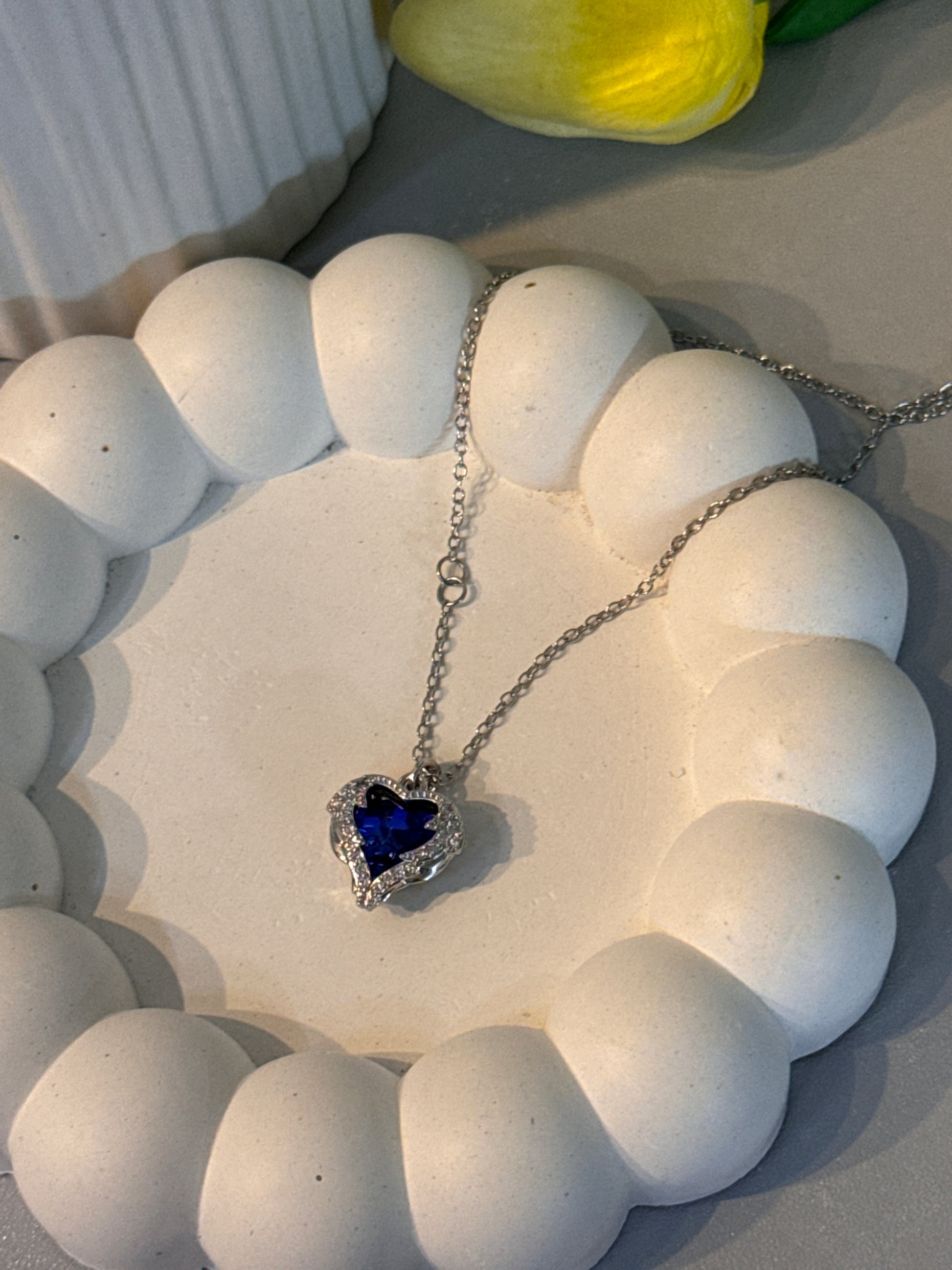 Necklace with a heart-shaped blue pendant on a white stone surface