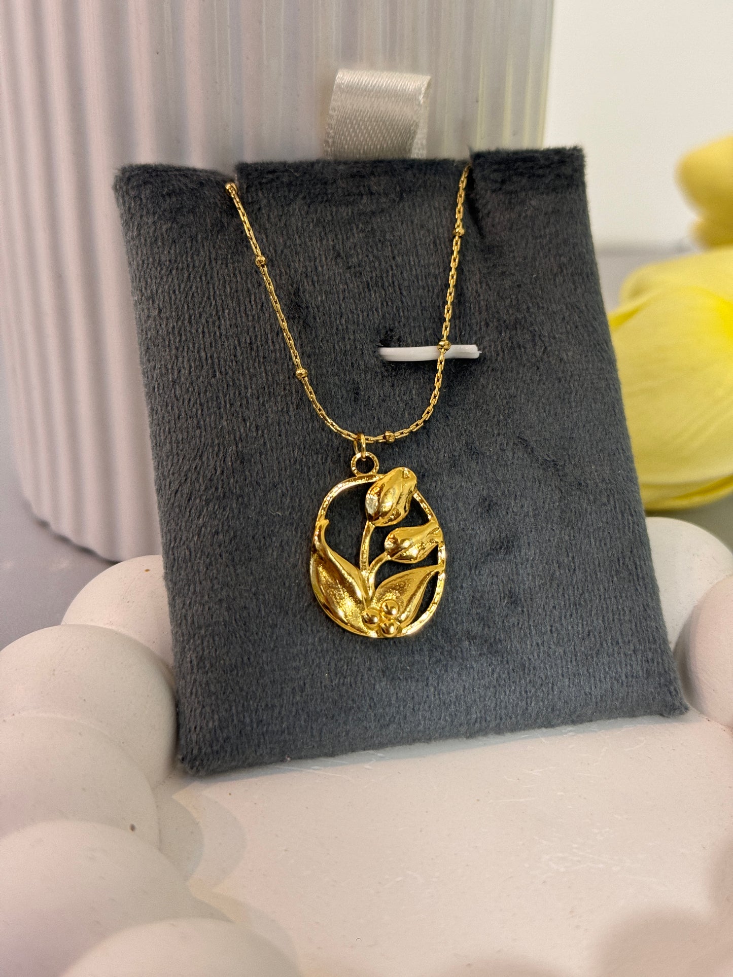 Gold necklace with a pendant on a gray cushion