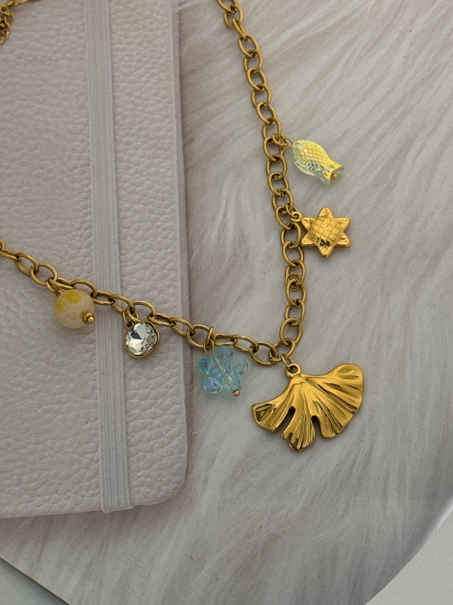 Gold chain bracelet with various charms on a white surface